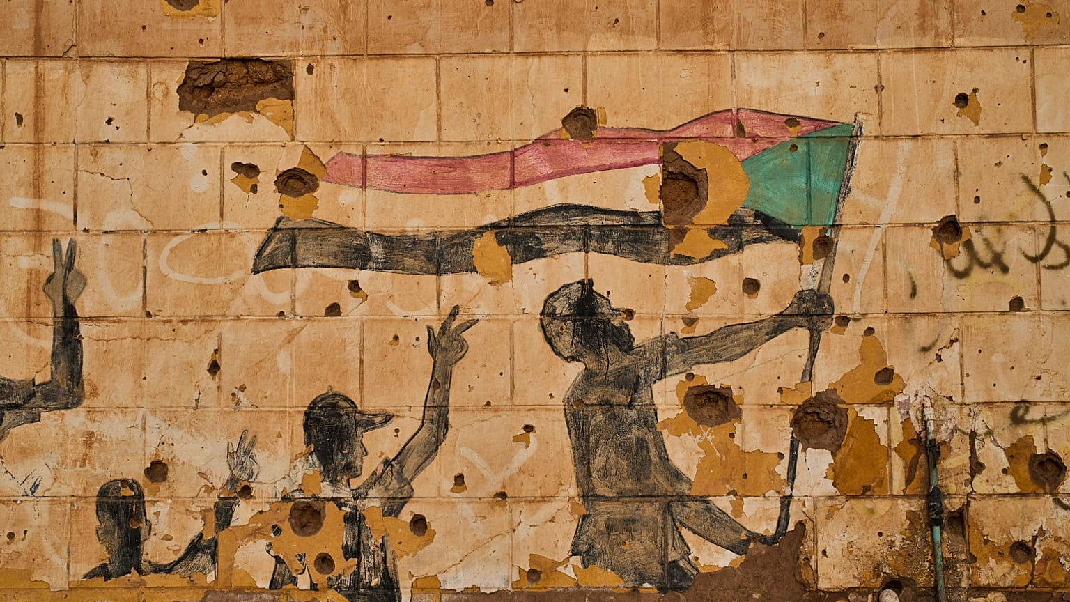 رسم جداري يُظهر أشخاصاً يرفعون العلم السوداني على جدار تضرر بالرصاص والشظايا في أم درمان، بضواحي الخرطوم، السودان، في 23 أبريل 2026.