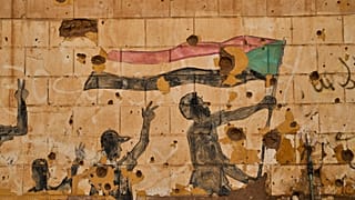 رسم جداري يُظهر أشخاصاً يرفعون العلم السوداني على جدار تضرر بالرصاص والشظايا في أم درمان، بضواحي الخرطوم، السودان، في 23 أبريل 2026.