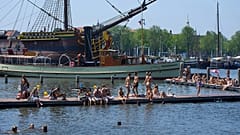 People cool off near the replica of a 18th-century VOC (Dutch East India Company) vessel during a heatwave in Amsterdam, Netherlands, Thursday, June 25, 2026.