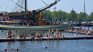 People cool off near the replica of a 18th-century VOC (Dutch East India Company) vessel during a heatwave in Amsterdam, Netherlands, Thursday, June 25, 2026.