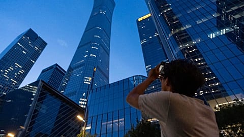 أحد المارة يحاول التقاط صورة للأضرار التي لحقت ببرج سيتيك المعروف أيضًا باسم برج زون في بكين، الصين، الجمعة 26 يونيو 2026. (AP Photo/هان جوان نج)