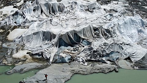 FILE - Matthias Huss, of the glacier monitoring group GLAMOS, stands at the Rhone Glacier that is partially covered with sheets near Goms, Switzerland, on June 10, 2025. 