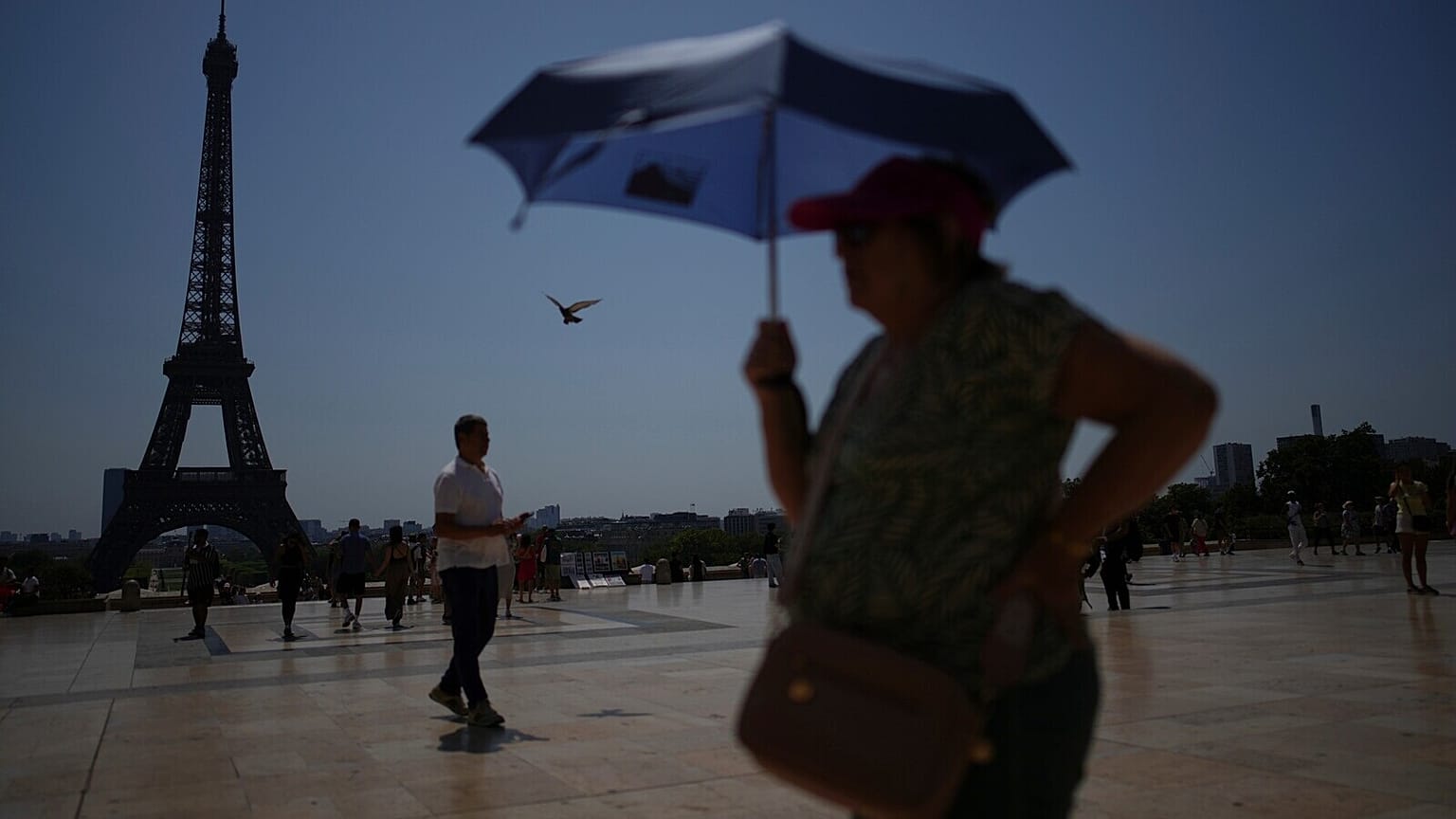 People walk at Trocadero plaza near the Eiffel Tower during a heat wave July 2, 2025, in Paris