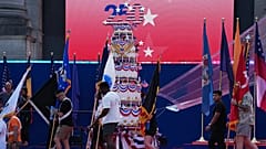 People carry flags past a giant birthday cake to celebrate during the America 250 event in Brussels,