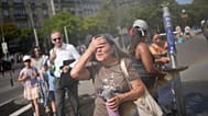 Tourists enjoy cooling off at a public water fountain In Paris, Friday, June 26, 2026. (AP Photo/Christophe Ena )