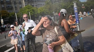 Tourists enjoy cooling off at a public water fountain In Paris, Friday, June 26, 2026. (AP Photo/Christophe Ena )