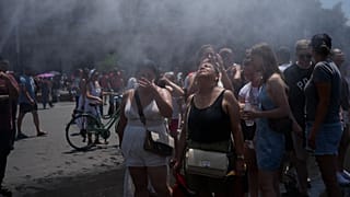 Des personnes se rafraîchissent devant un canon à eau installé par la municipalité de Rome