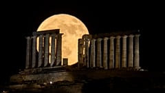 FILE - The strawberry Moon rises in the sky behind the ancient temple of Poseidon, about 70 km south of Athens, Greece, June 11, 2025. (AP Photo/Petros Giannakouris)