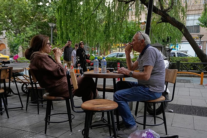 People drink coffee in the al fresco dining area of a cafe near the old main bazaar of Tehran, Iran