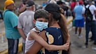 Ogleisys Cisneros sostiene a su hijo, Santiago Medina, mientras espera en la fila para recibir ayuda humanitaria del gobierno, días después del terremoto que azotó La Guaira