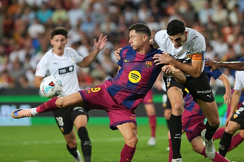 Robert Lewandowski, po lewej, oddaje strzał na bramkę w starciu z Cesarem Tarregą z Valencii podczas meczu hiszpańskiej La Ligi pomiędzy Valencią a FC Barceloną.