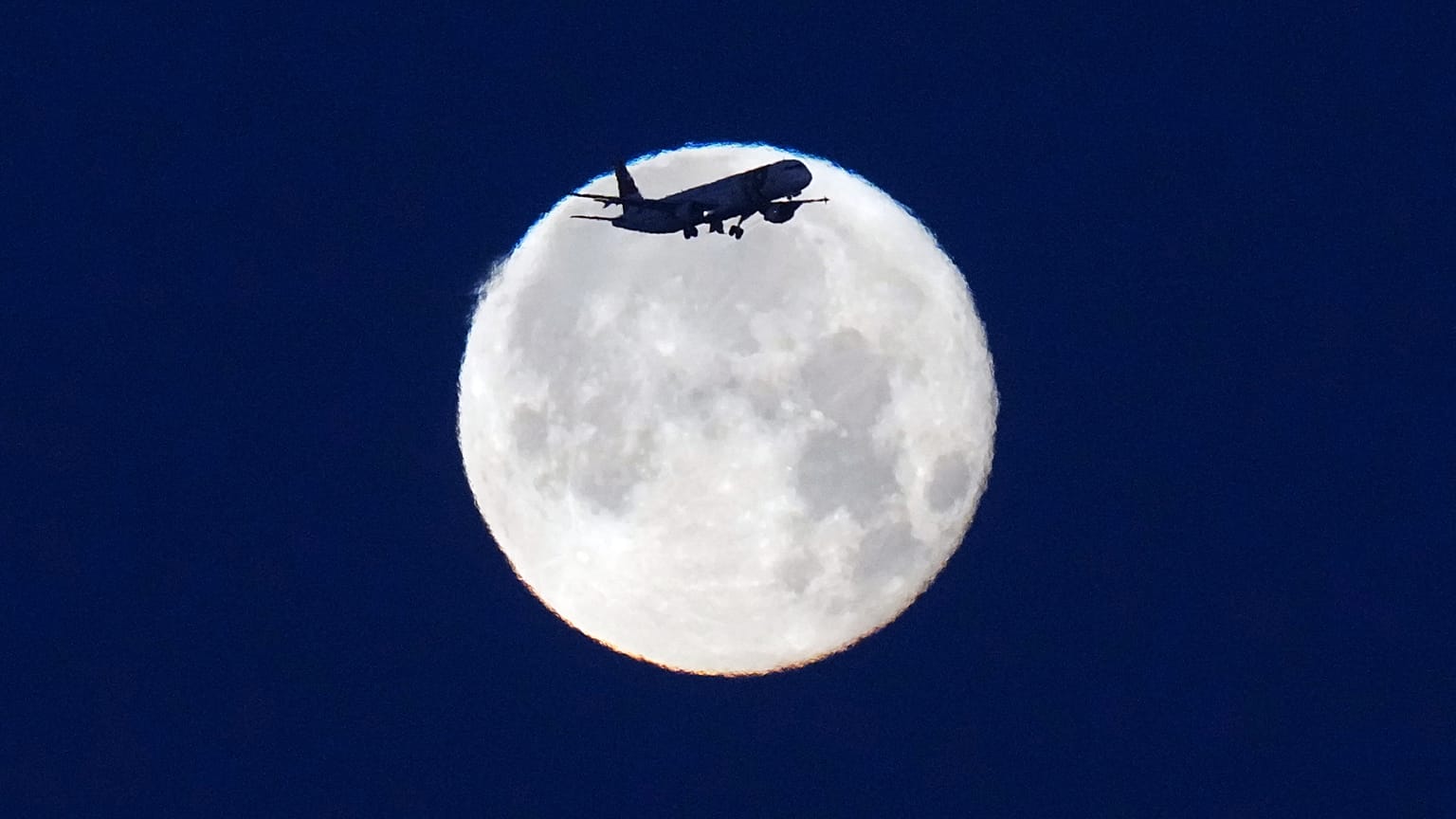 A TAP Air Portugal aircraft approaches landing in Lisbon at sunrise with the full moon behind it, Monday, June 1, 2026.