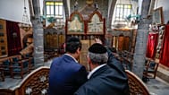 الحاخام يوسف حمرا، على اليمين، وابنه هنري يراقبان كتابًا مقدسًا قديمًا في كنيس إفرانج في مدينة دمشق القديمة في 18 فبراير 2025.