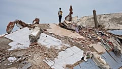 A man stands atop the rubble of a building that collapsed in the earthquakes in La Guaira, Venezuela, Tuesday, June 30, 2026.