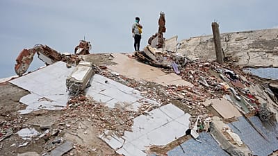 Un uomo è in piedi in cima alle macerie di un edificio crollato durante i terremoti a La Guaira, in Venezuela, martedì 30 giugno 2026.