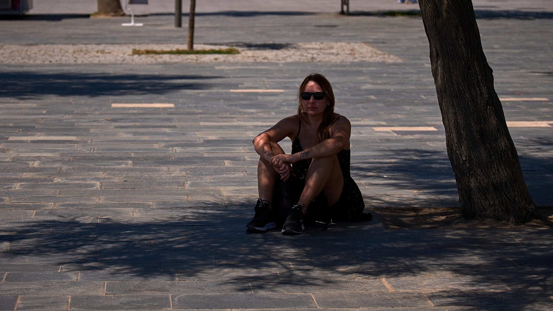 Uma mulher protege-se do sol à sombra de uma árvore em Barcelona, Espanha, na quarta-feira, 27 de maio de 2026. (Foto AP/Emilio Morenatti)
