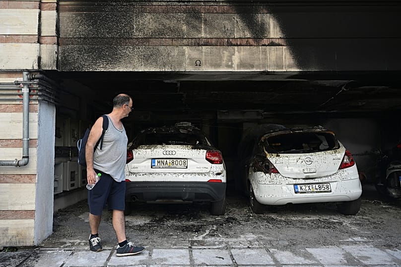 A man looks at burned vehicles following firebomb attacks that apparently targeted members of Greece's governing conservative New Democracy party in Thessaloniki, 1 July, 2026