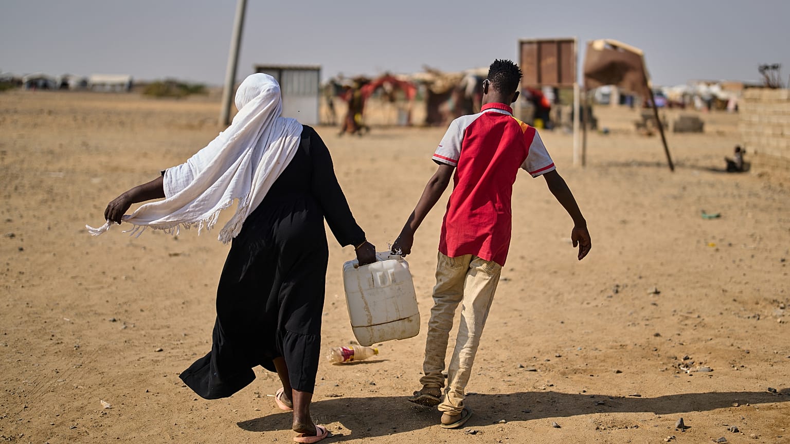 نازحون سودانيون داخليا يحملون المياه في مخيم الهشان على مشارف بورتسودان، السودان، الأربعاء 15 أبريل 2026. (AP Photo/بيرنات أرمانجو)