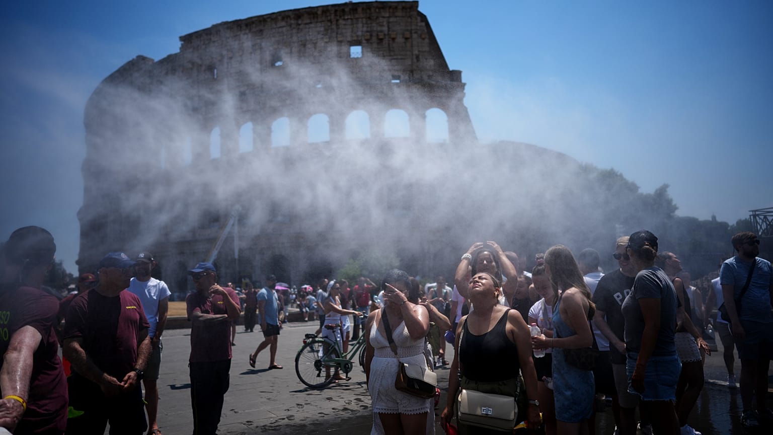 Personas se refrescan ante un cañón de agua del Ayuntamiento de Roma que alivia a turistas en el Coliseo y el Foro Romano, viernes 26 de junio de 2026