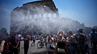 People cool off in front of a water-spraying cannon set up by Rome's municipality to relieve tourists at the Colosseum and Roman Forum, Rome, Friday, June 26, 2026