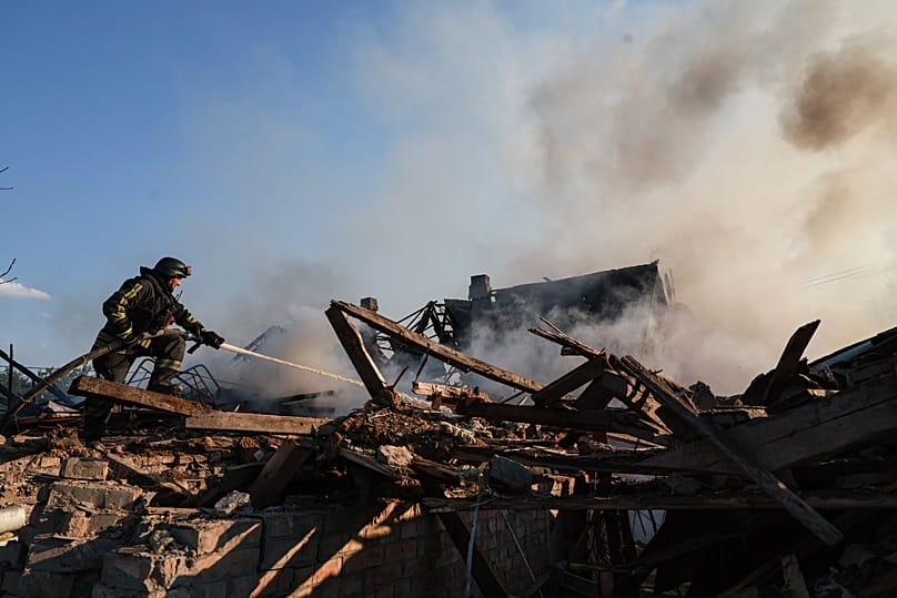 Спасатель тушит пожар в доме, разрушенном в результате российского удара по жилому кварталу в Запорожье, 30 июня 2026 года