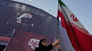 امرأة مؤيدة للحكومة تحمل علماً إيرانياً أسفل لافتة تعرض صورة للمرشد الأعلى الراحل علي خامنئي في ساحة بوسط العاصمة الإيرانية طهران، يوم الثلاثاء 30 يونيو 2026. 