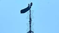Two people stand on the tip of the antenna of the Empire State Building while holding a banner, 1 July, 2026