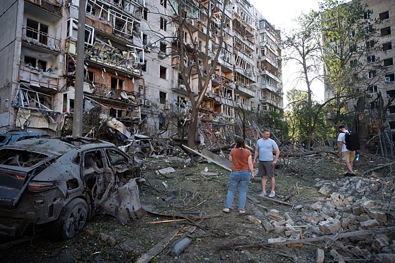 People look at a residential building damaged during the Russian missile attack in Kyiv, 2 July, 2026