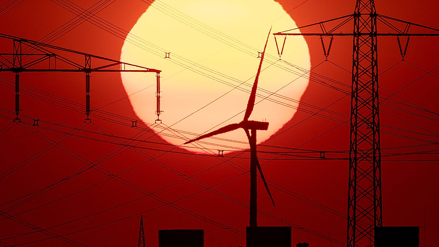 The sun rises behind power poles and a wind turbine in Frankfurt, Germany, early Saturday, July 27, 2019. 