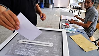 مسؤول انتخابي يراقب ناخباً يدلي بصوته خلال الانتخابات البرلمانية في الجزائر العاصمة، يوم الخميس 2 يوليو/تموز 2026. (صورة من وكالة أسوشيتد برس/فاتح غيدوم)