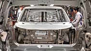 Workers complete an electric car on an assembly line during a press tour at a Volkswagen AG plant in Germany.