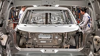 Workers complete an electric car on an assembly line during a press tour at a Volkswagen AG plant in Germany.