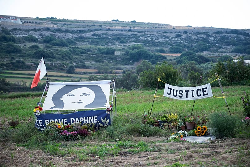 A drawing of Daphne Caruana Galizia and a banner reading 'Justice' during a silent gathering at the place where she was killed in Bidnija fields, 16 October, 2022