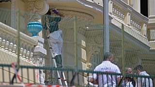 An investigator examines the scene at the residential building where an explosive device seriously injured three people a day earlier in Monaco, Tuesday, June 30, 2026.