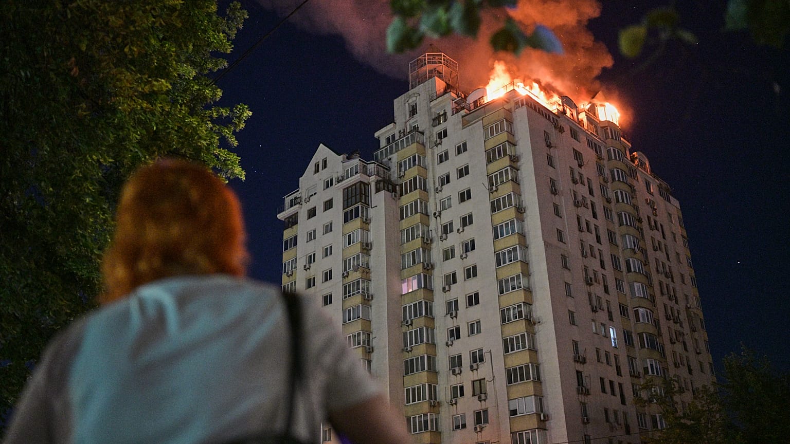 Bir kadın, Ukrayna’nın Kiev kentinde Rus füze saldırısının ardından yanan bir apartmanı izliyor, 2 Temmuz 2026 Perşembe.
