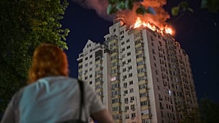 Bir kadın, Ukrayna’nın Kiev kentinde Rus füze saldırısının ardından yanan bir apartmanı izliyor, 2 Temmuz 2026 Perşembe.