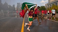 مشجع للبرتغال يركض عبر نافورة مياه، فيما يحاول المشجعون التخفيف من الحر قبيل مباراة دور الـ32 في كأس العالم 2026 بين البرتغال وكرواتيا