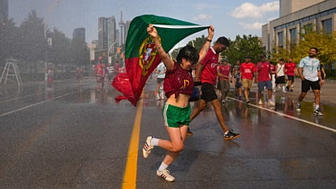 Un aficionado de Portugal corre bajo un chorro de agua, mientras los hinchas intentan refrescarse antes del partido de dieciseisavos del Mundial 2026 entre Portugal y Croacia