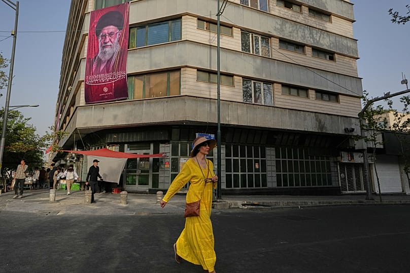 Una donna passa davanti a uno striscione con il ritratto dell’ayatollah iraniano Ali Khamenei, ucciso, in vista delle sue cerimonie funebri, a Teheran, 2 luglio 2026