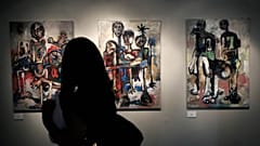 امرأة إلى سلسلة من ثلاث لوحات أكريليك على قماش تحمل اسم الحمامات، للفنان الفلسطيني إسماعيل دحلان، خلال معرض فني بعنوان "آثار، شهادة على الذاكرة" الضفة الغربية