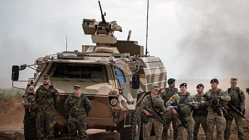 Bundeswehrsoldaten stehen während Übung "Grand Quadriga 2024" auf dem Truppenübungsplatz Pabradė neben einem gepanzerten Militärfahrzeug, 29. Mai 2024.
