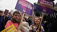 Unas mujeres se manifiestan con carteles “Igual salario ya” y “Solidaridad con las mujeres de todo el mundo”, durante el Día Internacional de la Mujer