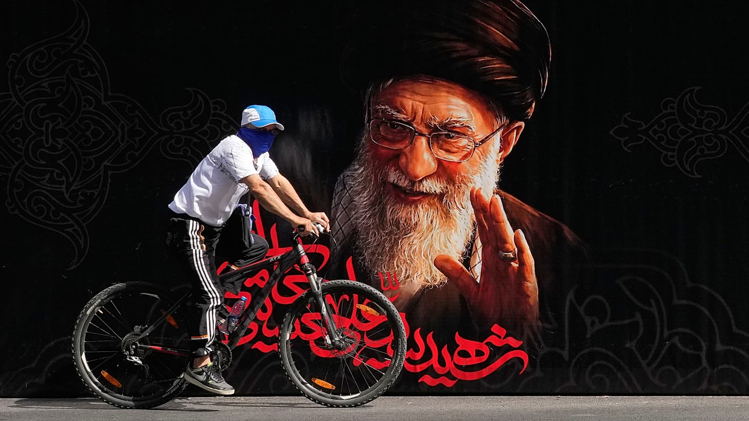 رجل يركب دراجة أمام صورة المرشد الأعلى الإيراني المقتول آية الله علي خامنئي قبل مراسم جنازته التي استمرت أيامًا في طهران، إيران، الجمعة 3 يوليو 2026