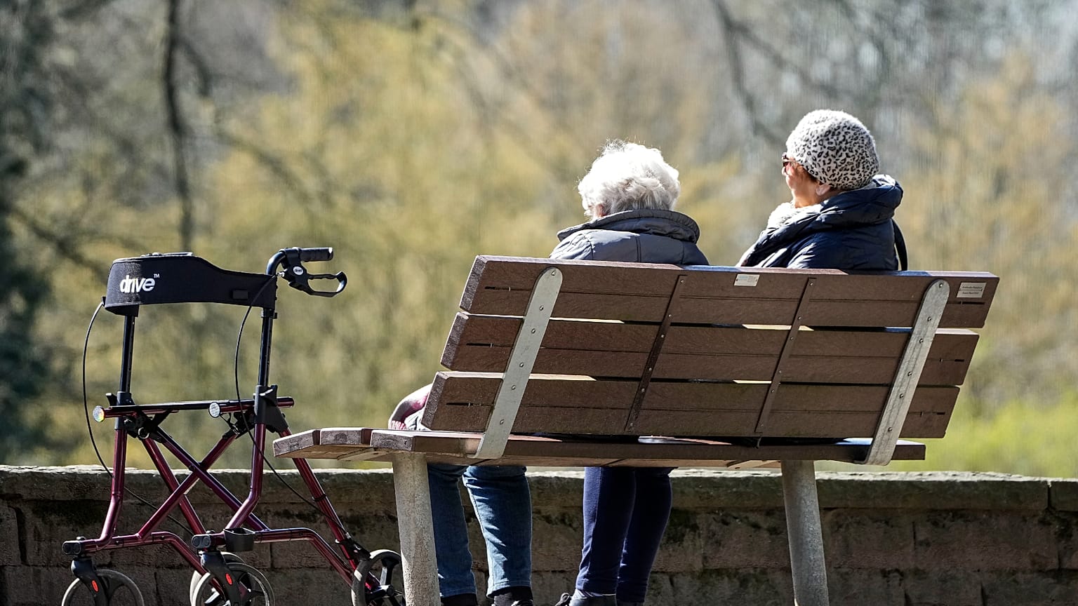 Ältere Frauen sitzen mit ihren Rollatoren auf einer Parkbank in der Sonne in einem Park in Gelsenkirchen am Mittwoch, dem 5. April 2023.