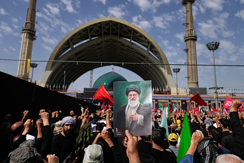يحمل أحد المشيعين صورة للمرشد الأعلى الإيراني الراحل آية الله علي خامنئي بينما يتجمع المشيعون لبدء مراسم جنازة خامنئي وأفراد عائلته 