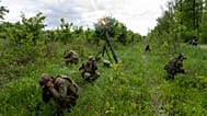 Ukrainian servicemen accompanied by members of the foreign legion fire mortars at Russian positions in the eastern region of Kharkiv, Ukraine, Tuesday, May 17, 2022.