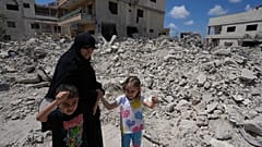 امرأة مع أطفالها تعود إلى قريتهم عقب الإعلان عن اتفاق وقف إطلاق النار الأولي بين الولايات المتحدة وإيران، تمر أمام منزلهم المدمر في قرية دير كانون جنوب لبنان