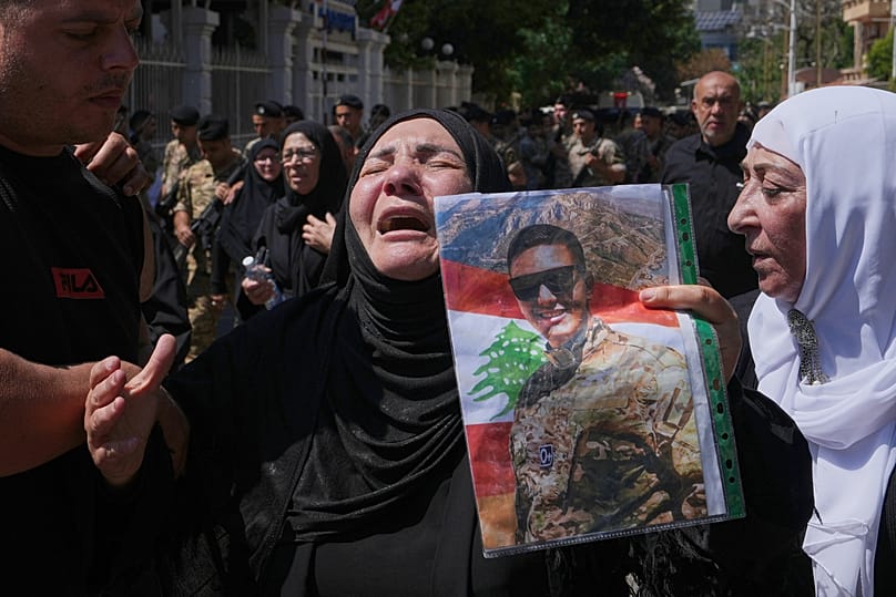 تنعى قريبة الجندي اللبناني حسن نزال، الذي قُتل السبت في جنوب لبنان مع عميد ونقيب في غارة جوية إسرائيلية، وهي تحمل صورته خلال موكب جنازته في بيروت، الأحد 7 يونيو 2026. (AP Phot