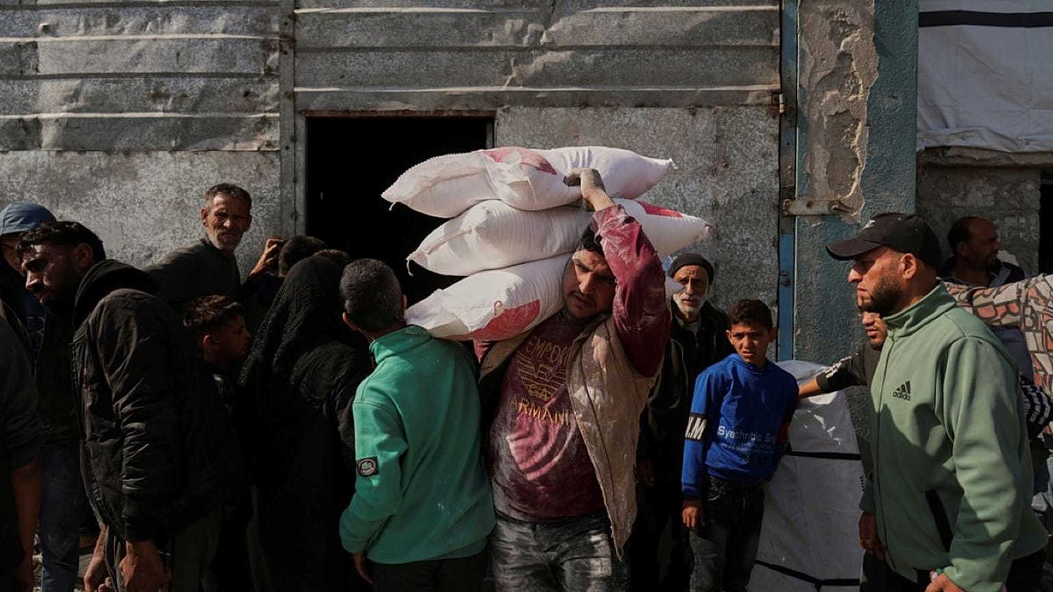 فلسطينيون يتسلمون أكياساً من الدقيق ومساعدات إنسانية أخرى وزعتها وكالة (الأونروا) في جباليا بقطاع غزة، يوم الثلاثاء 25 مارس/آذار 2025.