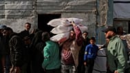 فلسطينيون يتسلمون أكياساً من الدقيق ومساعدات إنسانية أخرى وزعتها وكالة (الأونروا) في جباليا بقطاع غزة، يوم الثلاثاء 25 مارس/آذار 2025.